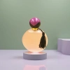 The pink round perfume bottle is equipped with a purple-black double-color ball-shaped cap and black tassels for decoration Application Scenario
